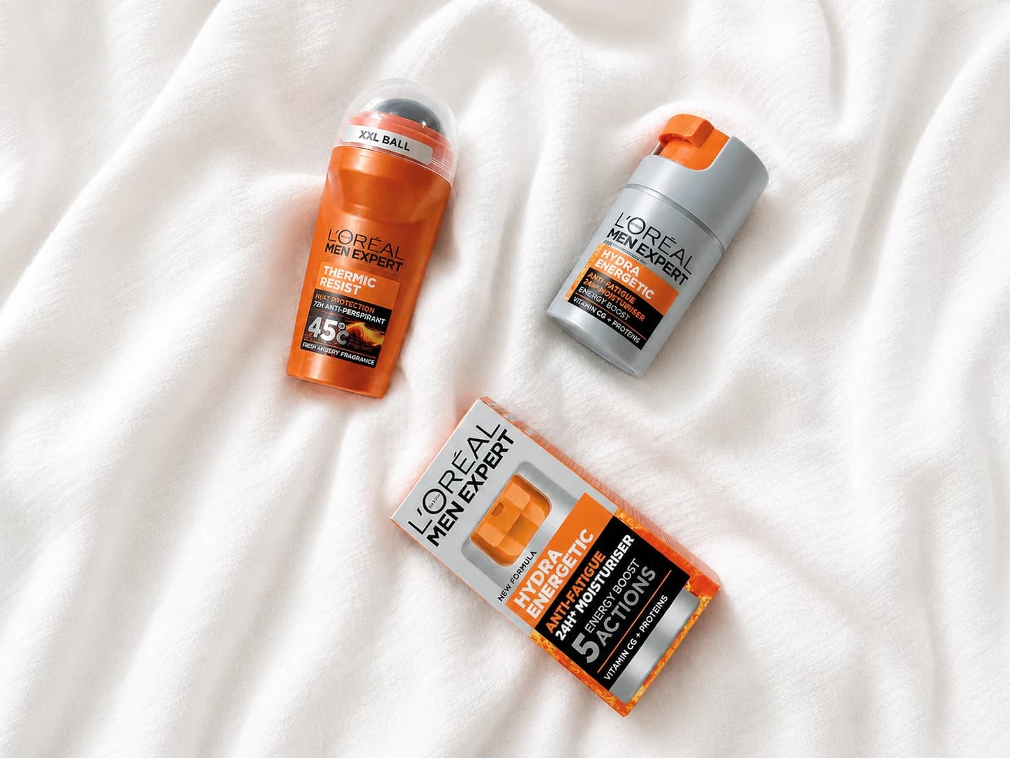 Trzy kosmetyki L’Oréal Men Expert na jasnej tkaninie: antyperspirant Thermic Resist oraz kremy Hydra Energetic